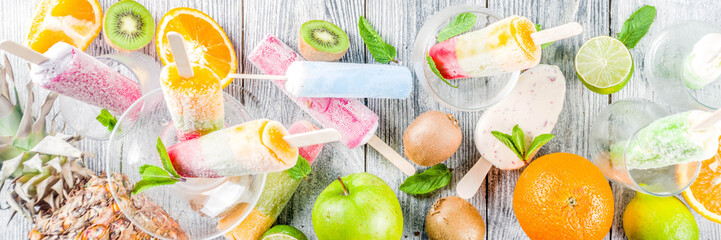 Wall Mural - Colorful fruit ice cream popsicle. Juicy gelato lollypops on sticks, with different fresh tropic fruits, wooden background copy space