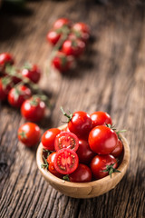 Wall Mural - Fresh cherry tomatoes in wooden bowl on old oak table