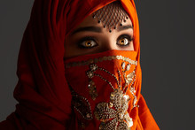 Studio Shot Of A Young Charming Woman Wearing The Terracotta Hijab Decorated With Sequins And Jewelry. Arabic Style.