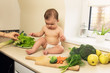 © Liliia - The baby in the diaper is sitting on the kitchen table. A child plays and has fun with fresh organic vegetables and fruits.