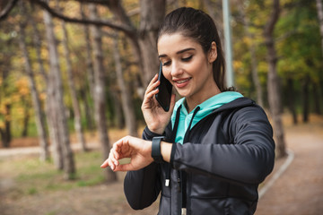 Wall Mural - Pretty fitness woman outdoors in the park looking at watch clock.