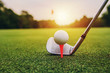 closeup golf club and golf ball on green grass wiht sunset