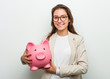 © Asier - Young european business woman holding a piggy bank happy, smiling and cheerful.