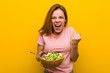 © Asier - Young healthy woman holding a salad cheering carefree and excited. Victory concept.