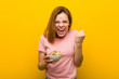 © Asier - Young woman holding a cereals bowl cheering carefree and excited. Victory concept.
