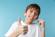 © Drobot Dean - Image of cheery caucasian boy 10-12y with freckles wearing white casual t-shirt and earpods looking at camera