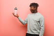 © Asier - Young fitness black man holding a water bottle impressed holding copy space on palm.