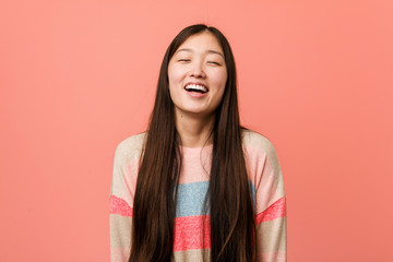 Young cool chinese woman relaxed and happy laughing, neck stretched showing teeth.