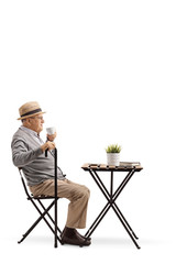 Canvas Print - Senior man with cane sitting and drinking coffee