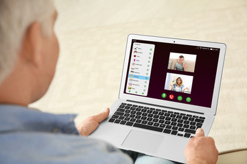 Wall Mural - Closeup view of senior man talking with family members via video chat at home