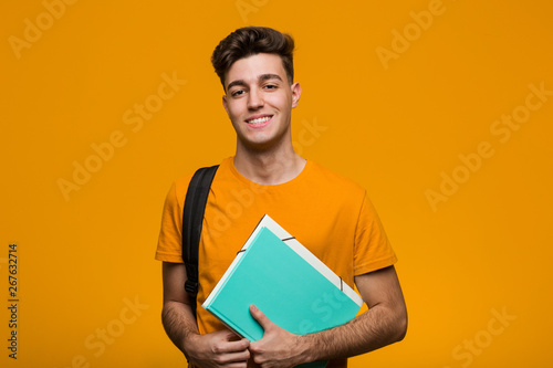 Fotografía Young student man holding books smiling and raising thumb up