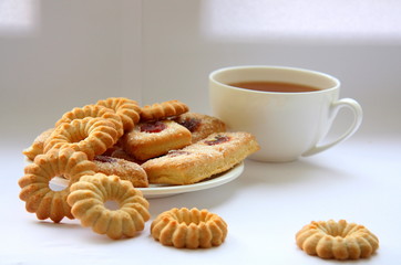 White cup with tea and biscuits.