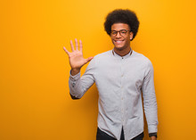 Young African American Man Over An Orange Wall Showing Number Five