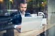 Leinwandbild Motiv Handsome businessman working on laptop and sitting in cafe