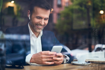 Wall Mural - Businessman talking  on phone through wireless headphones in cafe