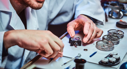 Wall Mural - Undistracted clockmaster is fixing old watch for a customer at his own workshop.