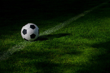 Black and white soccer ball on green soccer pitch