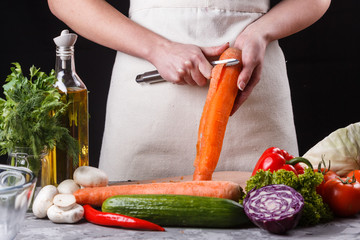 young woman in gray apron peeling carrots