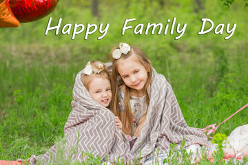 Two girls, sisters on green grass background with space for text. Happy family day concept.