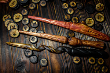 Homemade magic wands and wooden runes on a dark wooden background