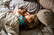 © Adam Hester - A toddler aged girl sleeping in a bed with a doll.
