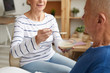 © Seventyfour - Mid section  portrait of smiling senior woman feeding husband lying on bed in recovery, copy space