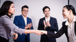 © PRASERT - Business people shaking hands, between meeting in seminar room
