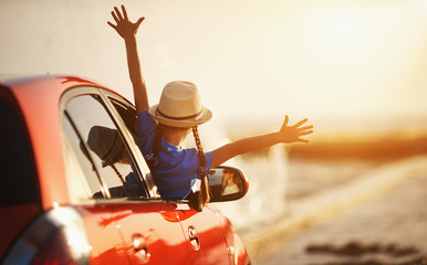 happy child girl goes to summer travel trip in car.