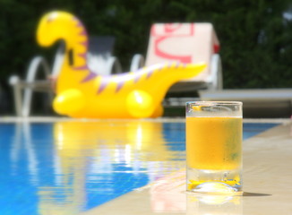  Transparent glass cup with lemonade or juice near the pool in the hot summer. Vacation. Pool. Cold drink.