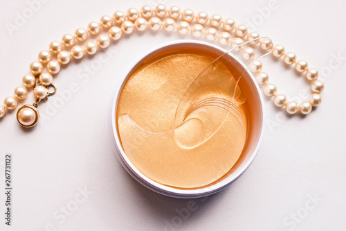 Fotografía Set of golden anti aging eye patches in the plastic jar and pearl necklace