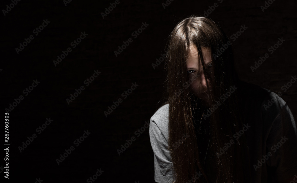 portrait of young teenager brunette girl with long hair in the Gothic style on a black background with copy space