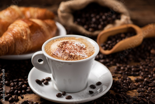 Cuadros en Lienzo A cup of cappuccino with coffee bean as background.