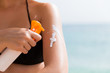 © sosiukin - Woman is putting sun lotion on her shoulder at the sea background