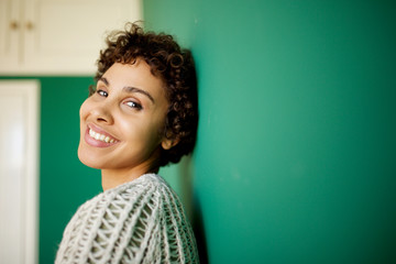 Close up side of happy african american woman smiling against green wall