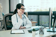 © PR Image Factory - young asian female doctor using mobile phone talking while sitting in hospital office. happy woman medical worker having joyful conversation with husband in break time. nurse resting in clinic.