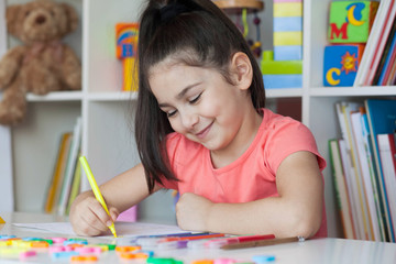 Happy cute child girl sitting at a table and drawing. Developmental activities. Back to school and happy time!