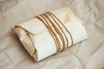 Wall Mural - Paper wrapped parcel with hemp cord on brown background. Package for delivery. 