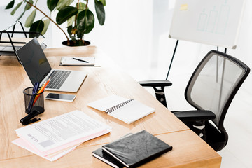 modern office with laptop, smartphone, resume and blank notebook on desk