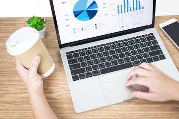 Poster - Side view picture of businessman analyzing financial graphs on the computer screen on a wooden table. Business concept.