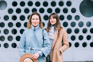 Portrait of two stylish adult serious emotion women siters walking in the city outdoor. Family, relations, growing upconcept.