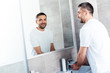© LIGHTFIELD STUDIOS - handsome smiling man washing hands in bathroom during morning routine
