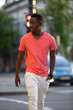 © antgor - African american man in living coral t-shirt walking at city street, casual style, crossing a road