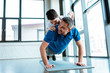 © LIGHTFIELD STUDIOS - Happy father doing push up exercise with son on back at gym with copy space
