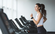 Young Woman Exercising On Treadmill And Listening Music