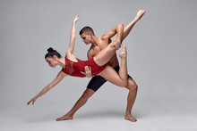 The Couple Of An Athletic Modern Ballet Dancers Are Posing Against A Gray Studio Background.