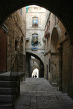 Fototapeta Na drzwi - Arched street in old city of Jerusalem with two unidentifiable people walking