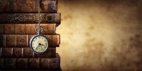 vintage clock hanging on a chain on the background of old books. old watch as a symbol of passing ti