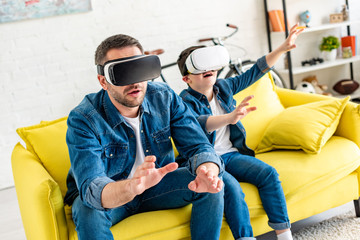 Canvas Print - father and son in vr headsets experiencing Virtual reality on couch at home