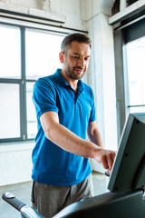 Wall Mural - handsome man working out on treadmill at gym