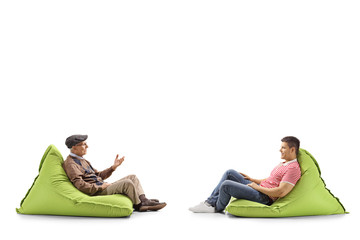 Wall Mural - Young and elderly man sitting on bean bags and talking